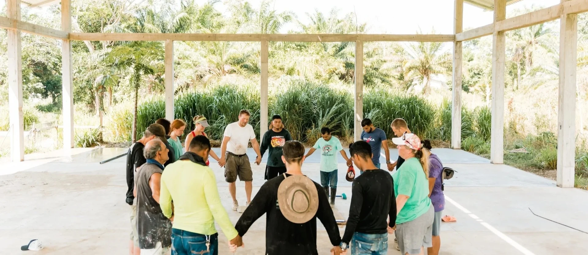 A circle of believers praying together on the ground of a future church build